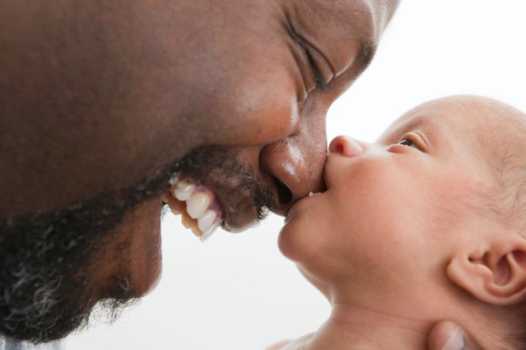 Baby biting nose of laughing father